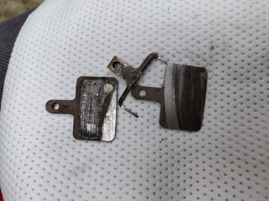 anciennes plaquettes sur lesquelles on ne voit plus de patin de frein mais simplement le support en acier, le ressort de rappel est tordu